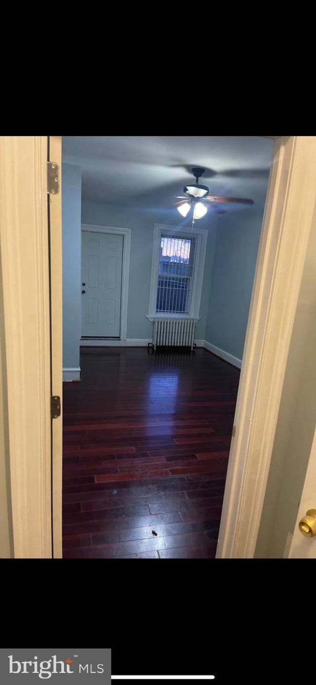 unfurnished room featuring radiator, ceiling fan, and dark hardwood / wood-style floors