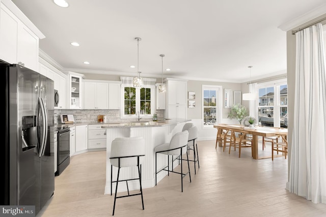 kitchen with a kitchen island, light wood-type flooring, stainless steel fridge with ice dispenser, hanging light fixtures, and white cabinets