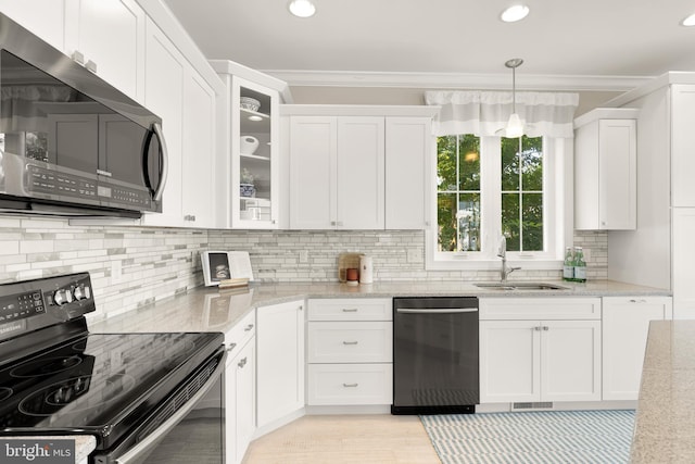 kitchen with stainless steel appliances, light stone counters, white cabinets, sink, and pendant lighting