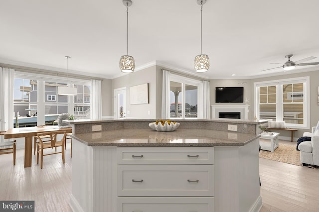 kitchen with hanging light fixtures, ceiling fan, a healthy amount of sunlight, and light wood-type flooring