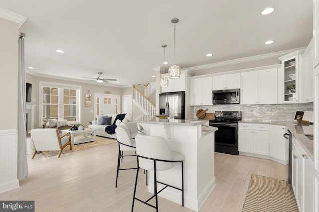 kitchen with white cabinets, light wood-type flooring, appliances with stainless steel finishes, and hanging light fixtures