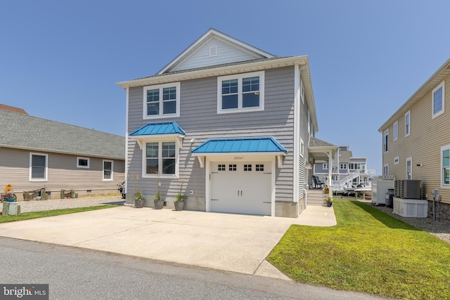 view of front of house with a garage, cooling unit, and a front yard