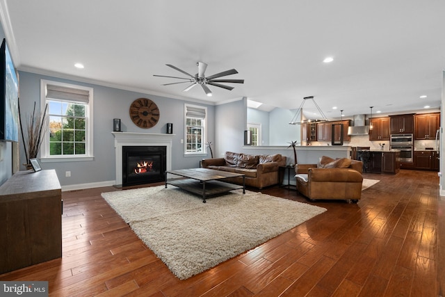 living room with dark hardwood / wood-style flooring, ceiling fan, and ornamental molding