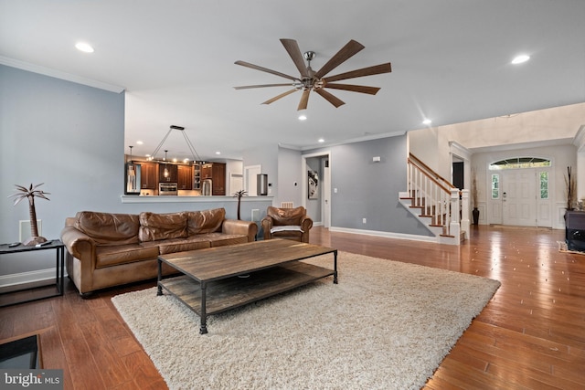 living room featuring hardwood / wood-style floors, ceiling fan with notable chandelier, and crown molding