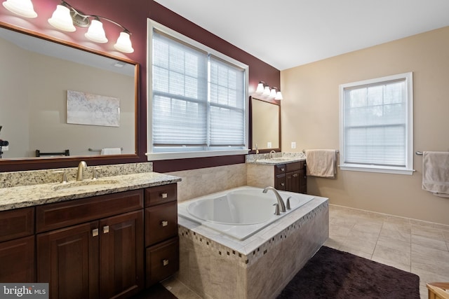 bathroom featuring tiled tub, tile patterned flooring, vanity, and a healthy amount of sunlight