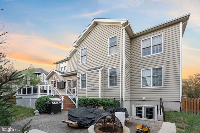 back house at dusk with a patio area, a sunroom, and an outdoor fire pit