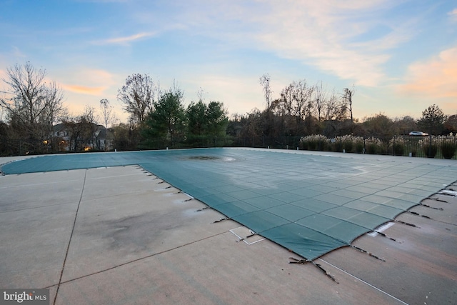 pool at dusk with a patio area