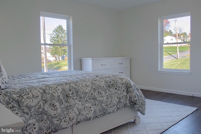 bedroom with dark hardwood / wood-style floors and multiple windows