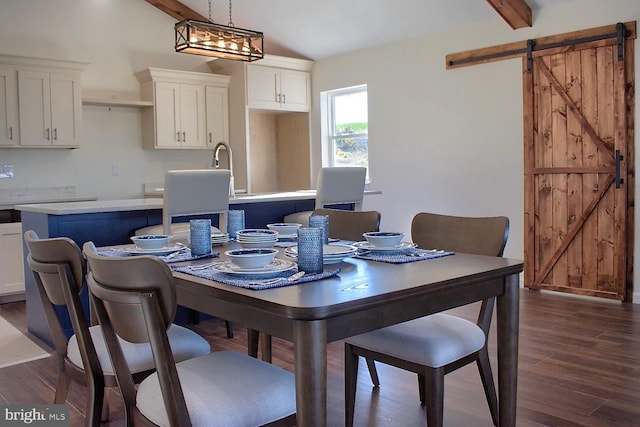 dining area with lofted ceiling with beams, a barn door, dark hardwood / wood-style floors, and sink