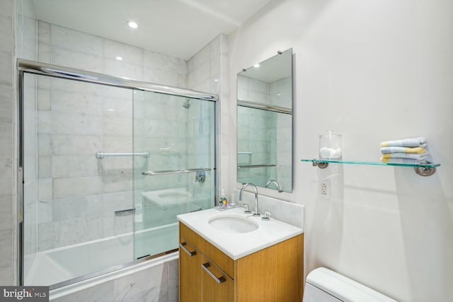 full bathroom featuring toilet, combined bath / shower with glass door, and vanity