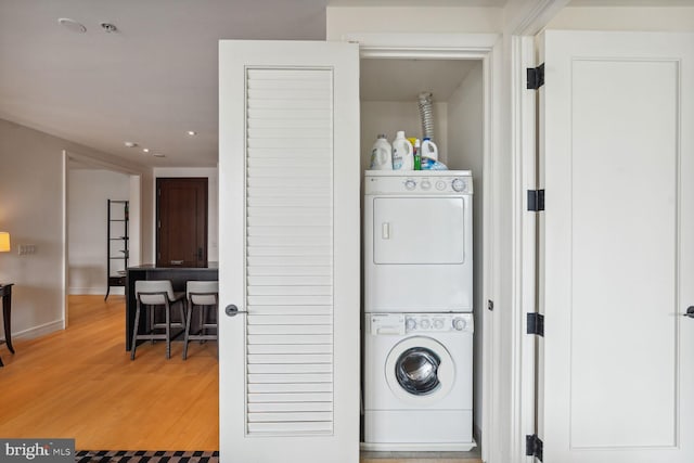 laundry area with hardwood / wood-style flooring and stacked washer / dryer