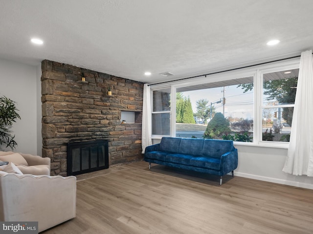 living room with a fireplace, light hardwood / wood-style flooring, and a textured ceiling