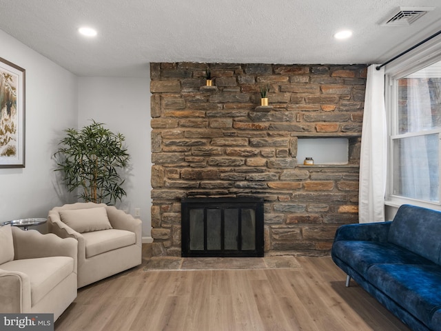 living room with a fireplace, wood-type flooring, and a textured ceiling