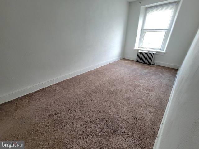 empty room featuring radiator and light colored carpet