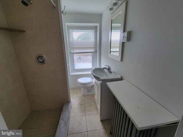 bathroom with tile patterned flooring, vanity, toilet, and a tile shower