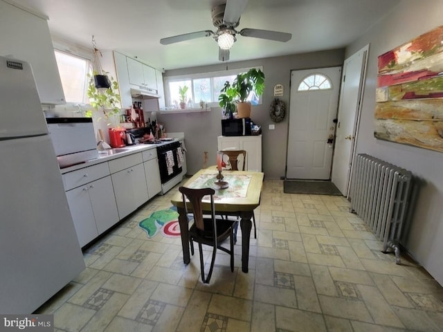 kitchen featuring radiator, white cabinetry, white appliances, and ceiling fan