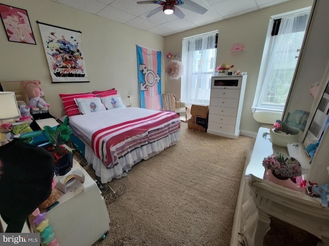 carpeted bedroom featuring ceiling fan and a drop ceiling