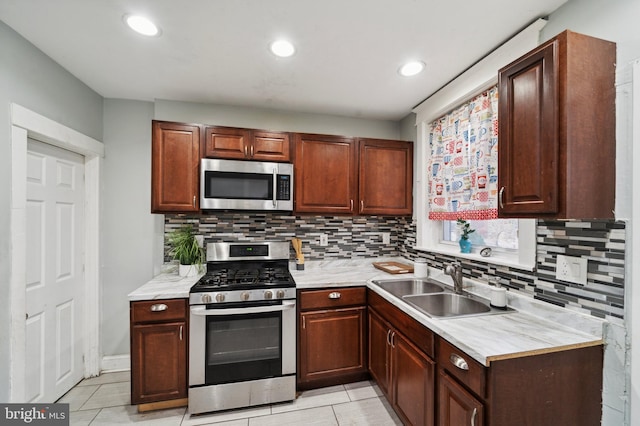 kitchen with decorative backsplash, sink, light tile patterned floors, and stainless steel appliances