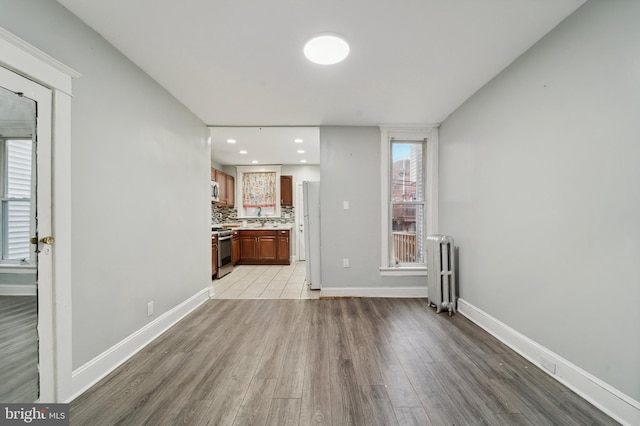 unfurnished living room with light wood-type flooring and radiator heating unit