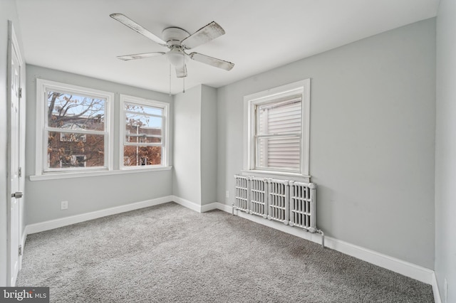 empty room featuring carpet flooring, ceiling fan, and radiator