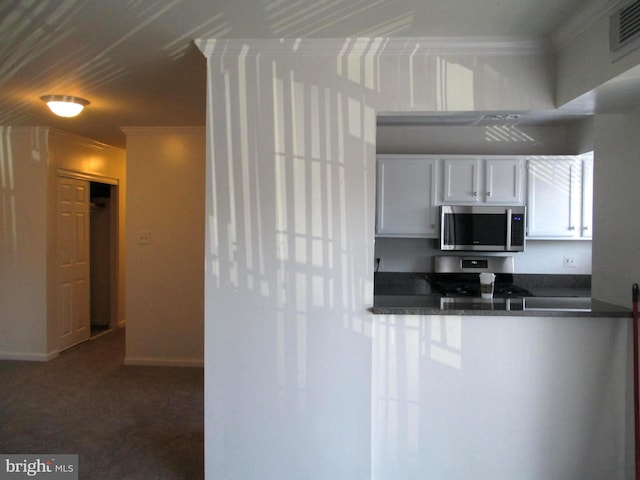 kitchen with white cabinets, stainless steel appliances, and ornamental molding