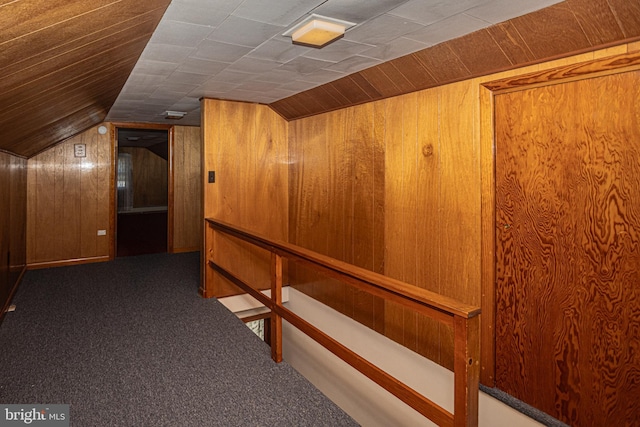 hall with wood walls, vaulted ceiling, and carpet floors