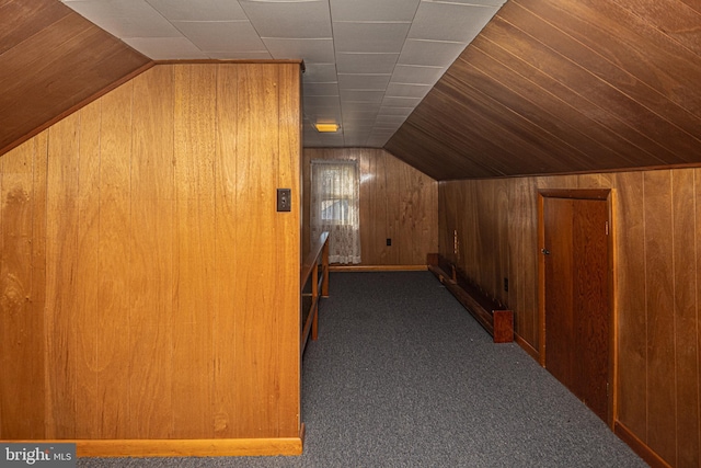 bonus room with wood walls, vaulted ceiling, and dark colored carpet