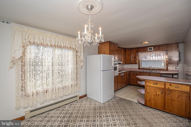 kitchen with white refrigerator, a notable chandelier, hanging light fixtures, sink, and baseboard heating