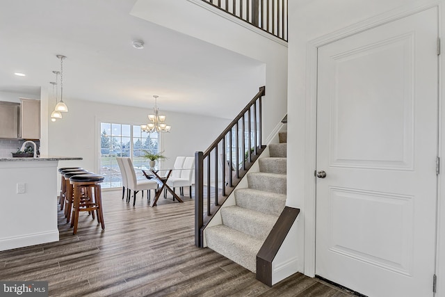 staircase with wood-type flooring and a chandelier