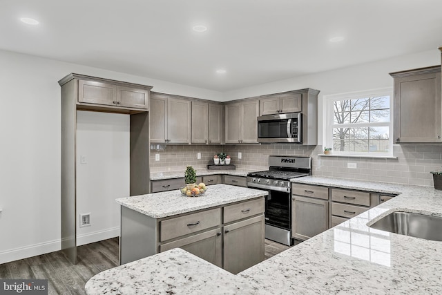 kitchen with dark wood-type flooring, light stone counters, tasteful backsplash, and appliances with stainless steel finishes