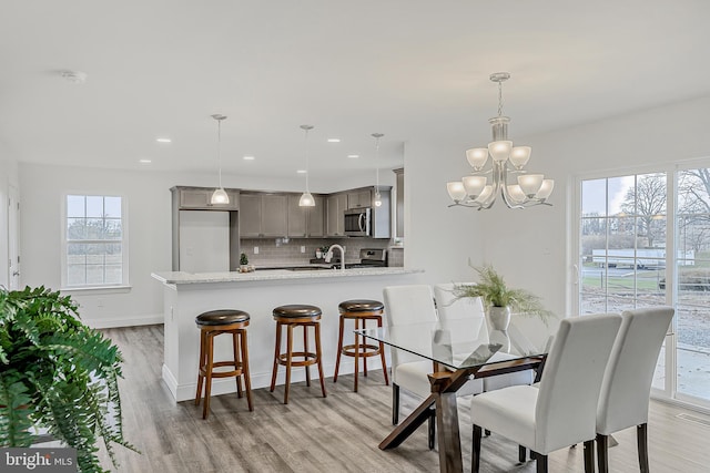 dining area featuring light hardwood / wood-style flooring, a notable chandelier, and sink