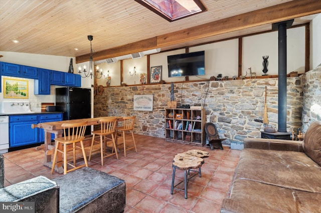 interior space featuring tile patterned floors, wood ceiling, an inviting chandelier, a wood stove, and lofted ceiling with skylight