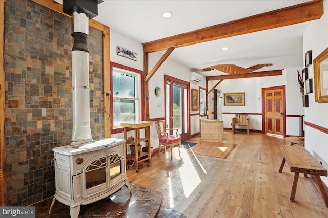 interior space with light hardwood / wood-style floors, a wood stove, tile walls, a wall mounted AC, and beamed ceiling