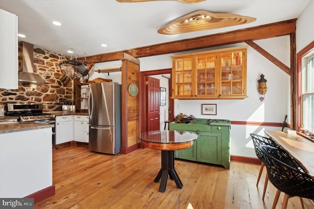 kitchen featuring light wood-type flooring, appliances with stainless steel finishes, wall chimney exhaust hood, and white cabinets