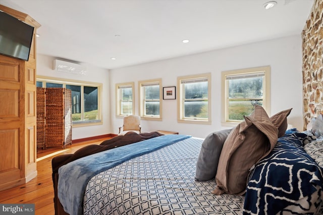 bedroom featuring a wall mounted AC and light hardwood / wood-style floors