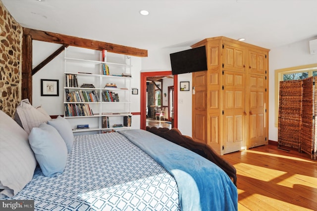 bedroom with hardwood / wood-style floors and beam ceiling