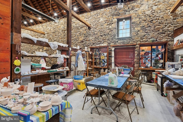 dining area with high vaulted ceiling and beam ceiling