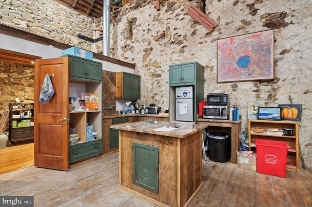 kitchen with a towering ceiling, hardwood / wood-style flooring, and a center island