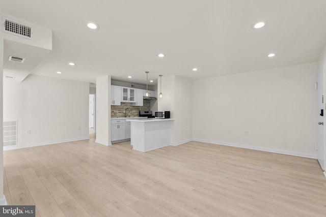 unfurnished living room featuring sink and light hardwood / wood-style floors