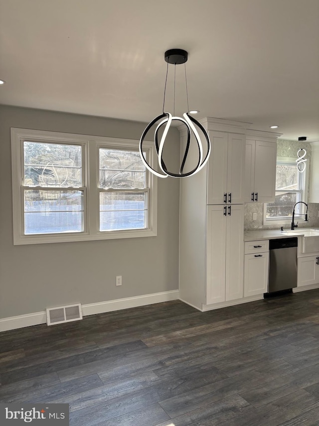 kitchen featuring sink, hanging light fixtures, stainless steel dishwasher, dark hardwood / wood-style flooring, and white cabinets