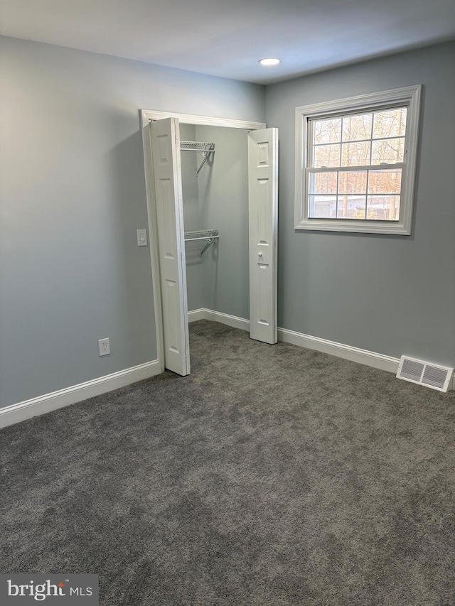 unfurnished bedroom featuring a closet and dark colored carpet