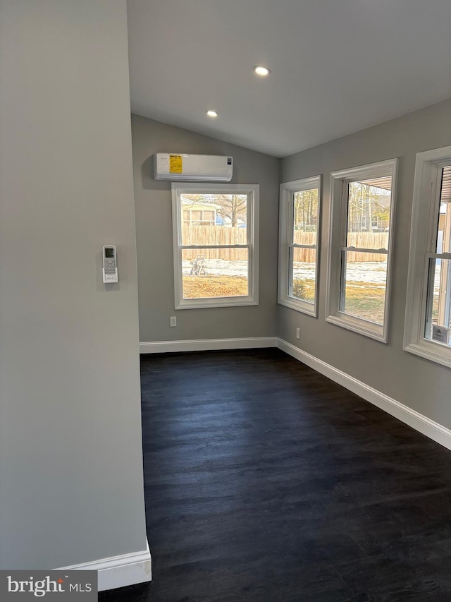 empty room featuring a wall mounted AC and vaulted ceiling