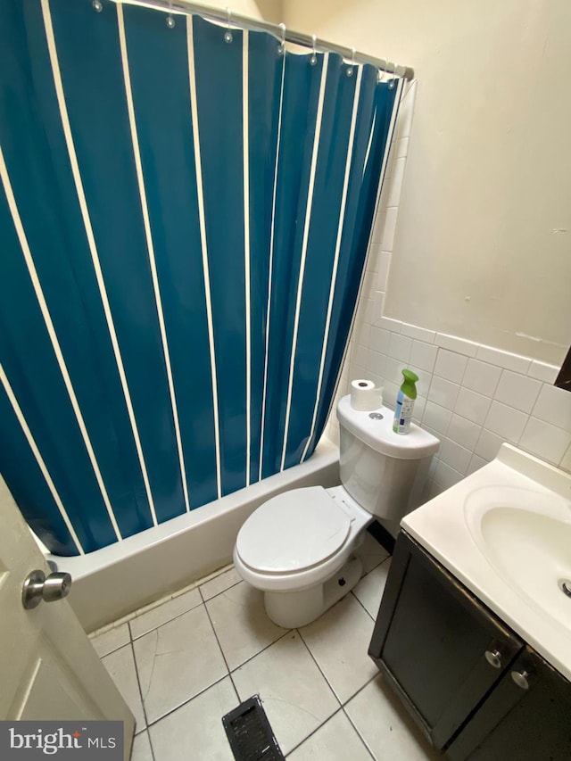 bathroom with toilet, vanity, tile patterned floors, and tile walls