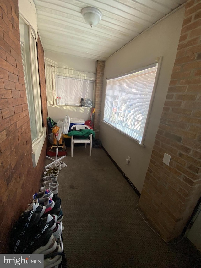 corridor with dark carpet and brick wall