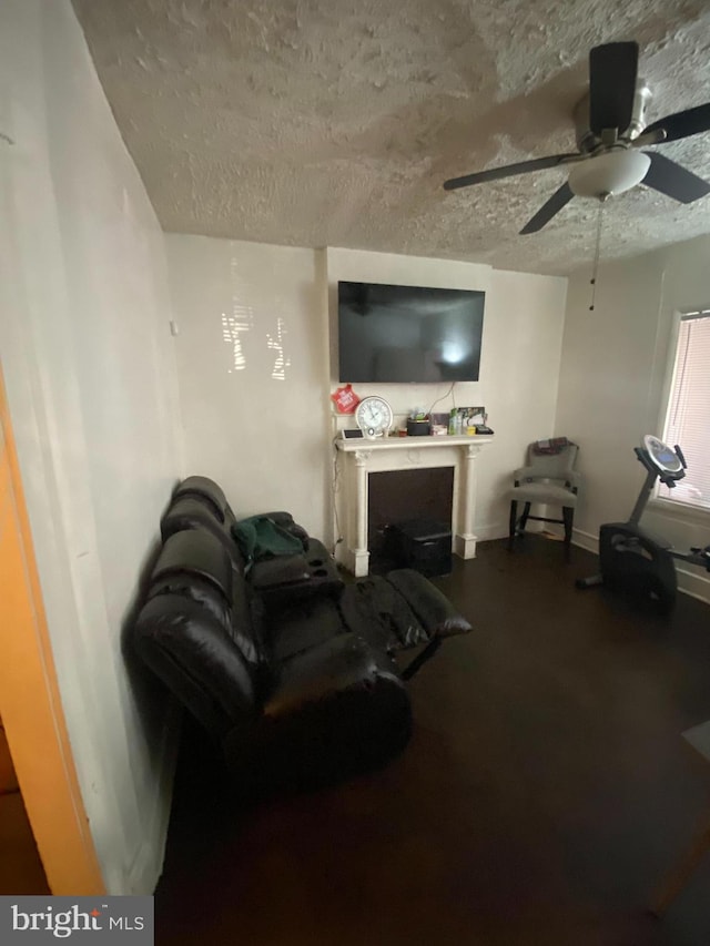 living room featuring ceiling fan and a textured ceiling