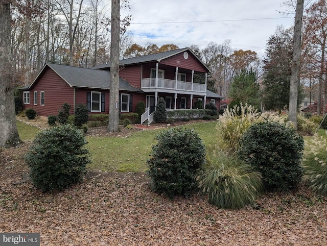 rear view of house with a porch, a yard, and a balcony