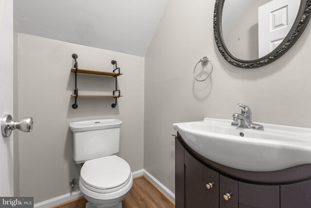 bathroom with vanity, wood-type flooring, vaulted ceiling, and toilet