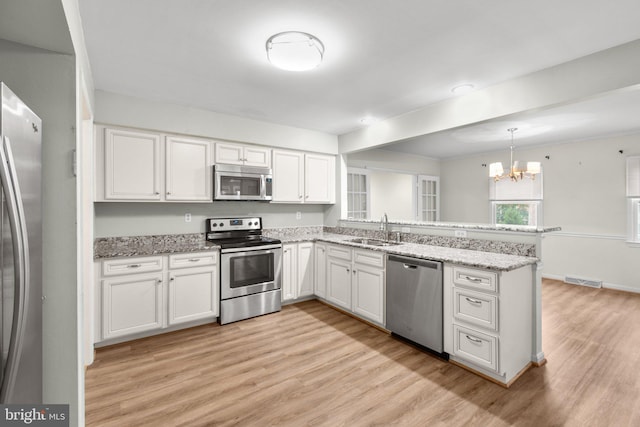 kitchen with hanging light fixtures, white cabinetry, sink, and appliances with stainless steel finishes