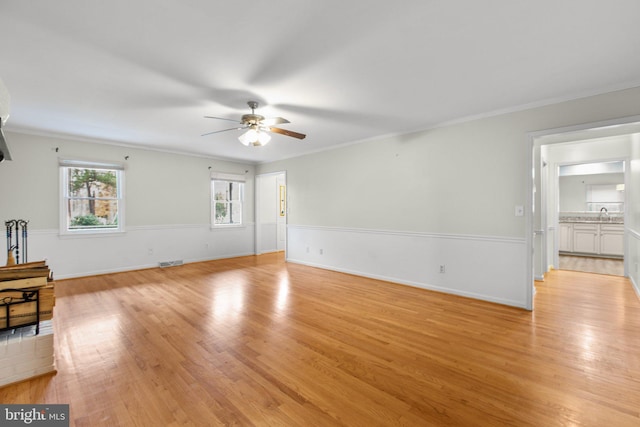 unfurnished living room with ceiling fan, crown molding, and light hardwood / wood-style flooring