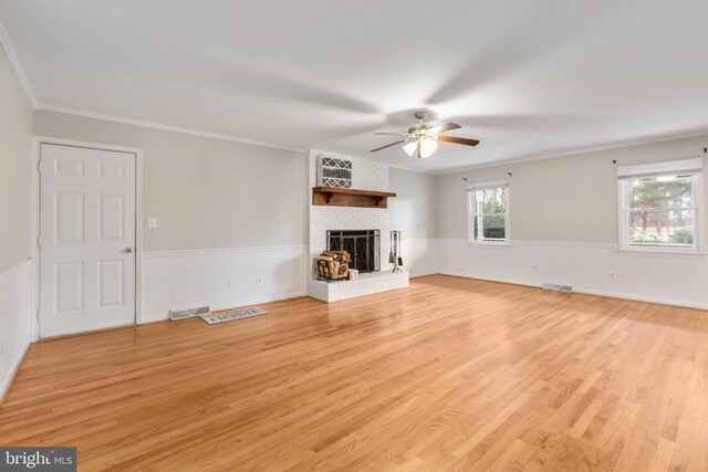 unfurnished living room with ceiling fan, light wood-type flooring, crown molding, and a brick fireplace